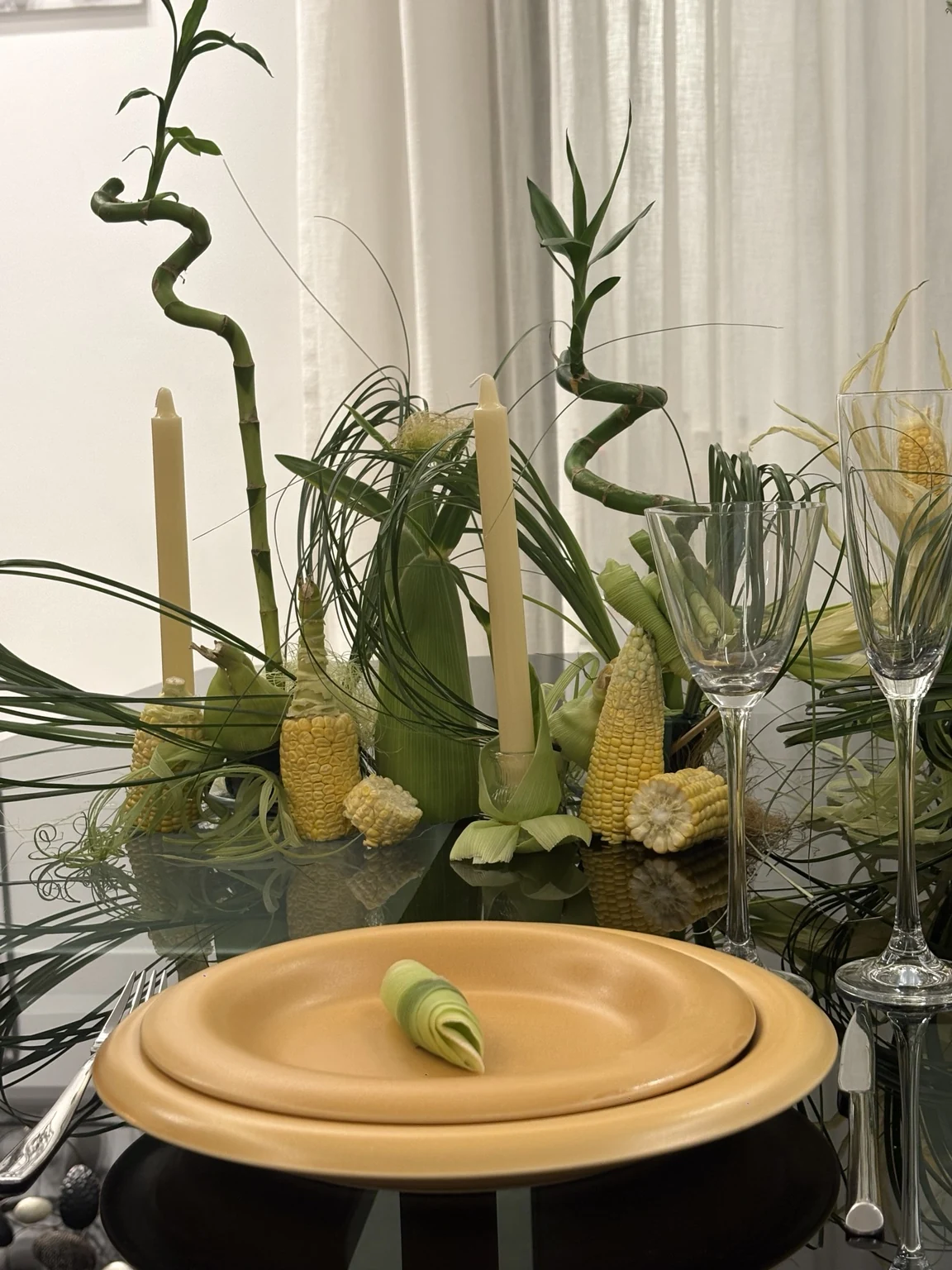 Sculptural botanical arrangement with black tabletop and plates