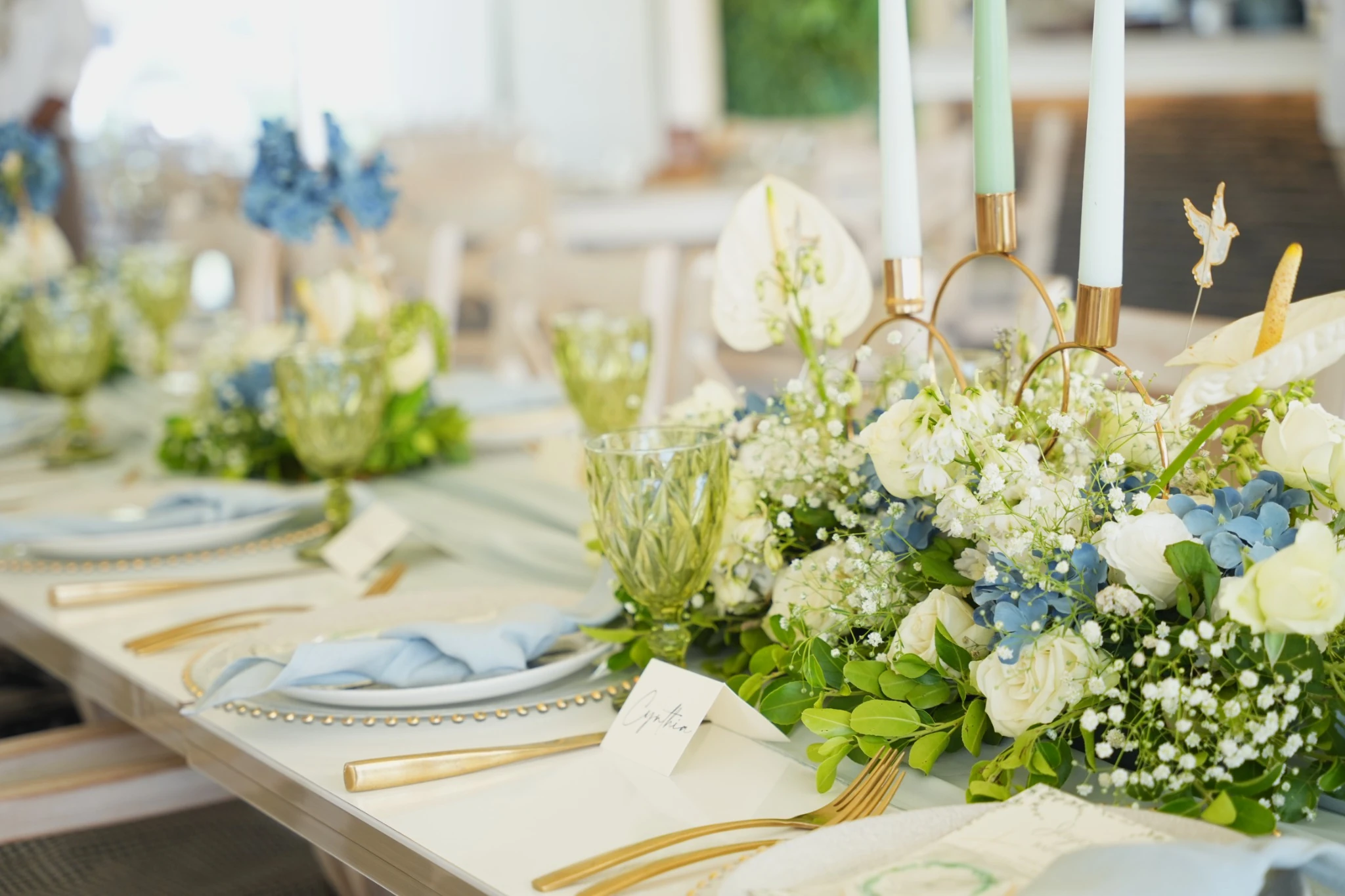 Table styling details with blue hydrangeas, candles and gold flatware