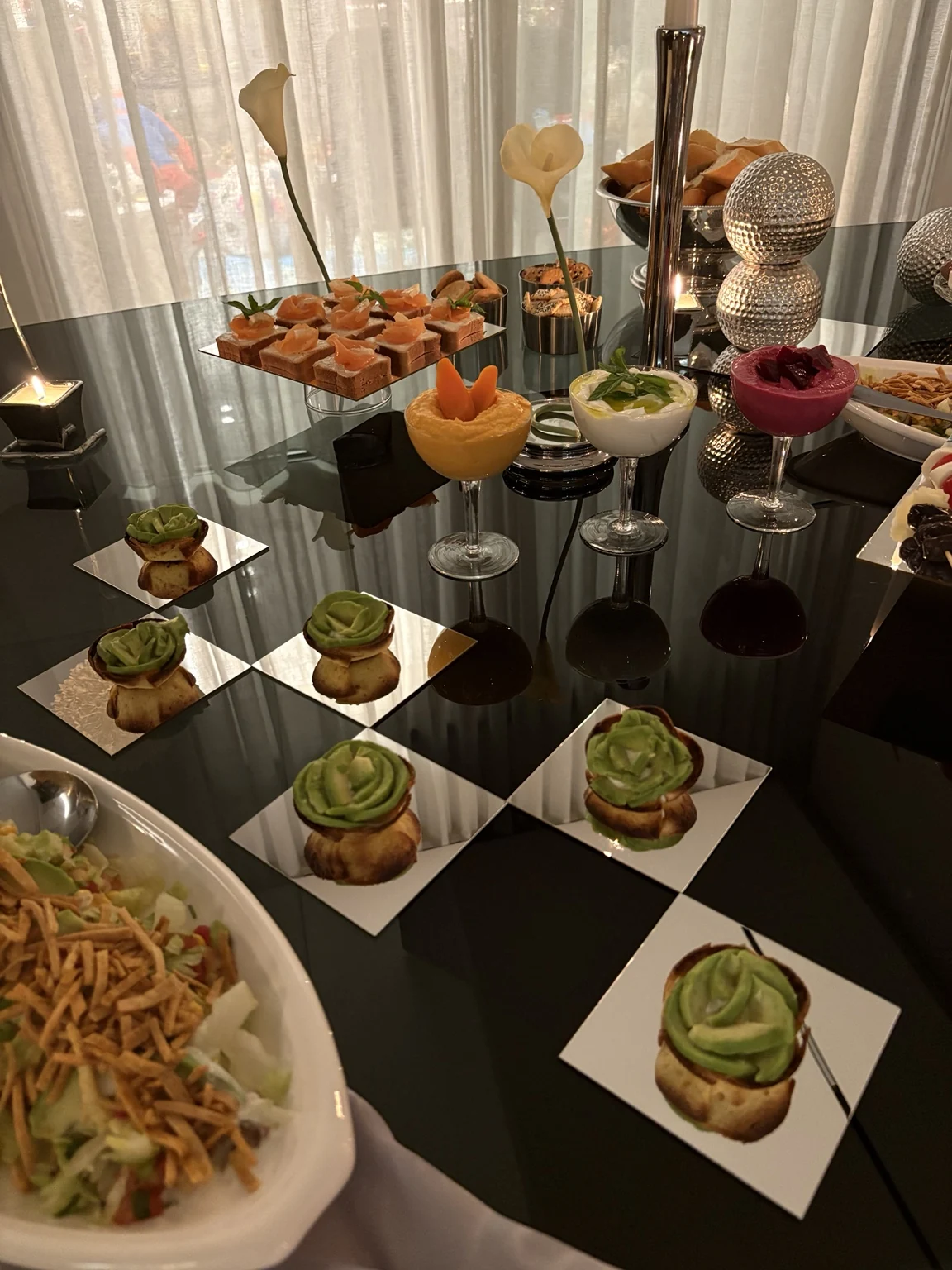 Individual canapés and colorful appetizers reflected on a black tabletop